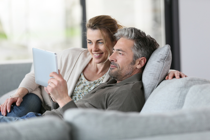 Mature couple using digital tablet relaxing in sofa